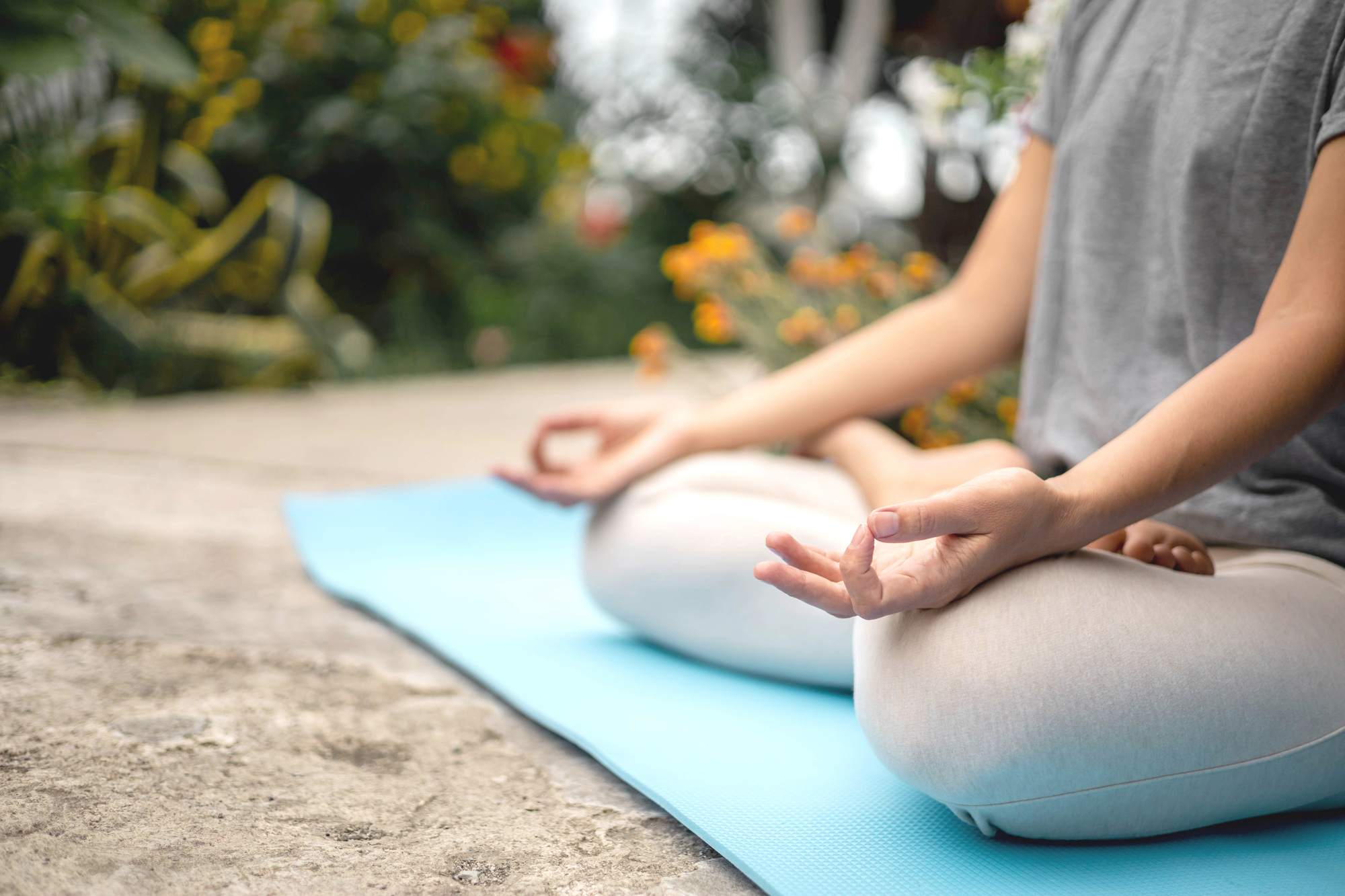 Concentrated woman sitting in lotus position yoga at summer garden park plants and blossom flowers