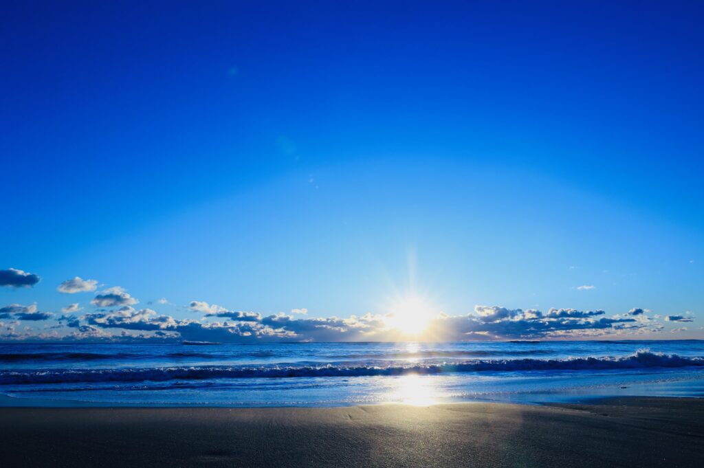 水平線から昇る太陽と青い空