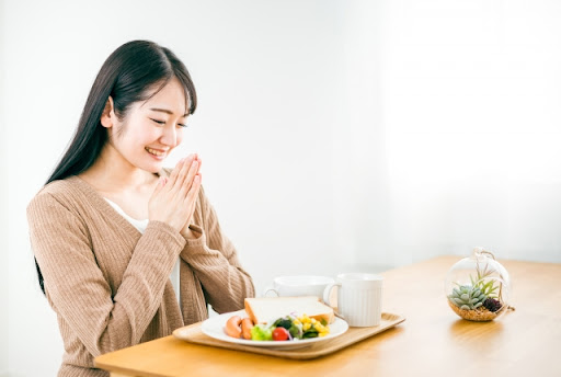 朝食を前に手を合わせる女性