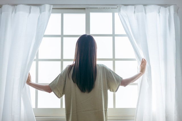 起床後カーテンを開ける女性